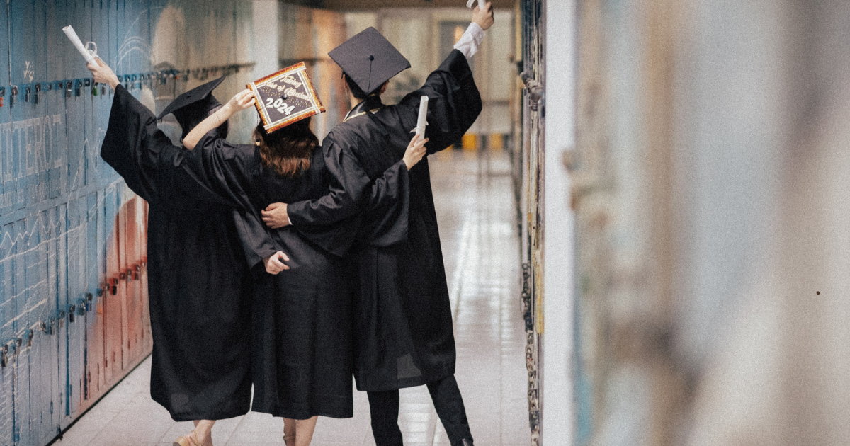 studenci w togach z podniesionymi rękoma z radości