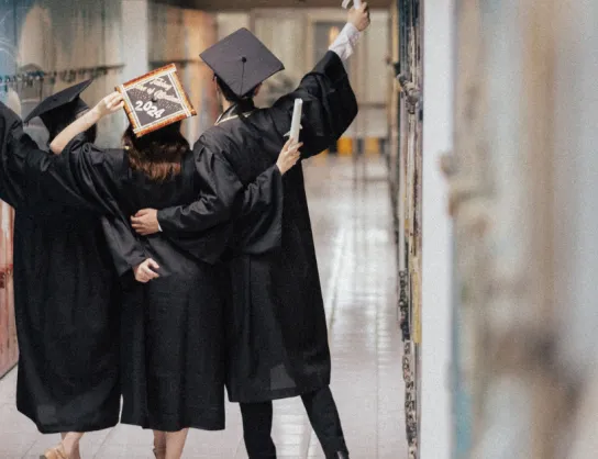 studenci w kitlach z podniesionymi w rękoma w geście radości 